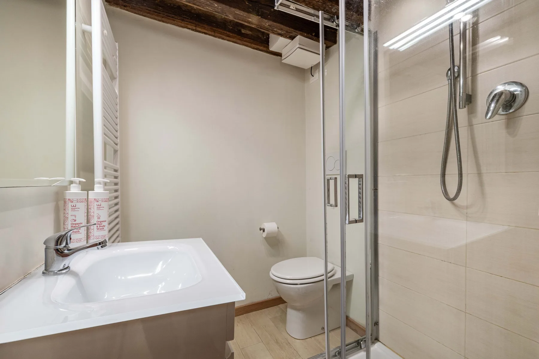 Un baño con lavabo y ducha con mampara de vidrio.