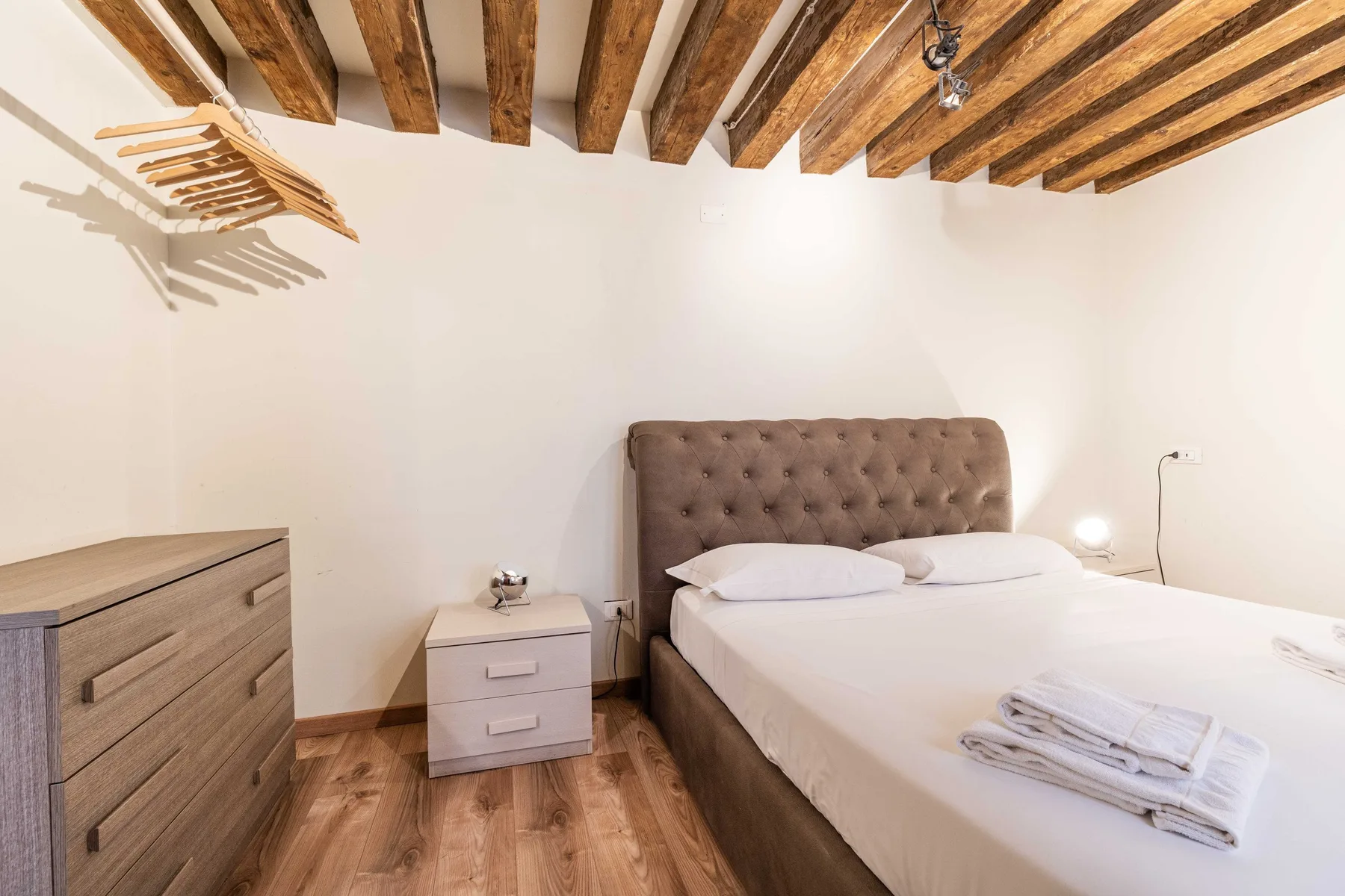 Un dormitorio con una cama doble, mesillas de noche y vigas de madera a la vista.