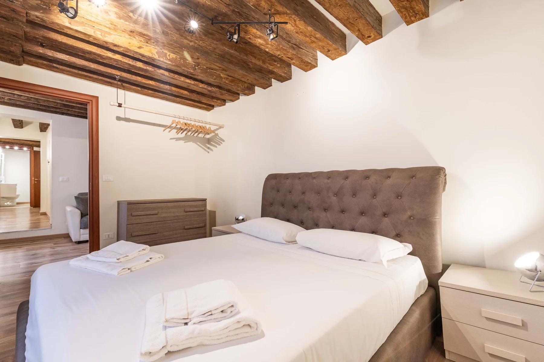 Un dormitorio con una cama grande, una mesita de noche y vigas de madera a la vista.