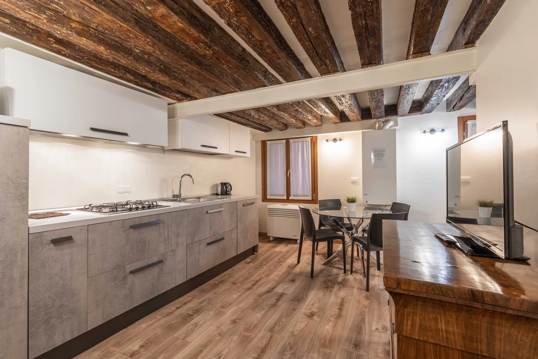 Cocina y comedor con vigas de madera en el techo y una mesa.