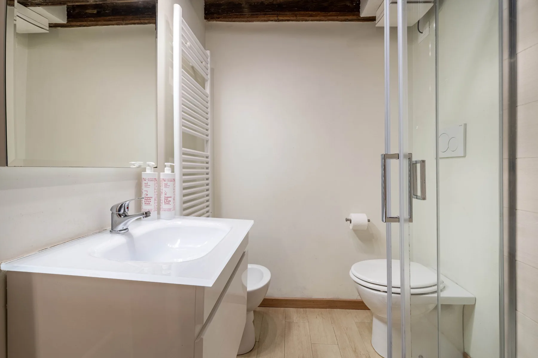 Un baño luminoso con lavabo, inodoro y ducha de vidrio.