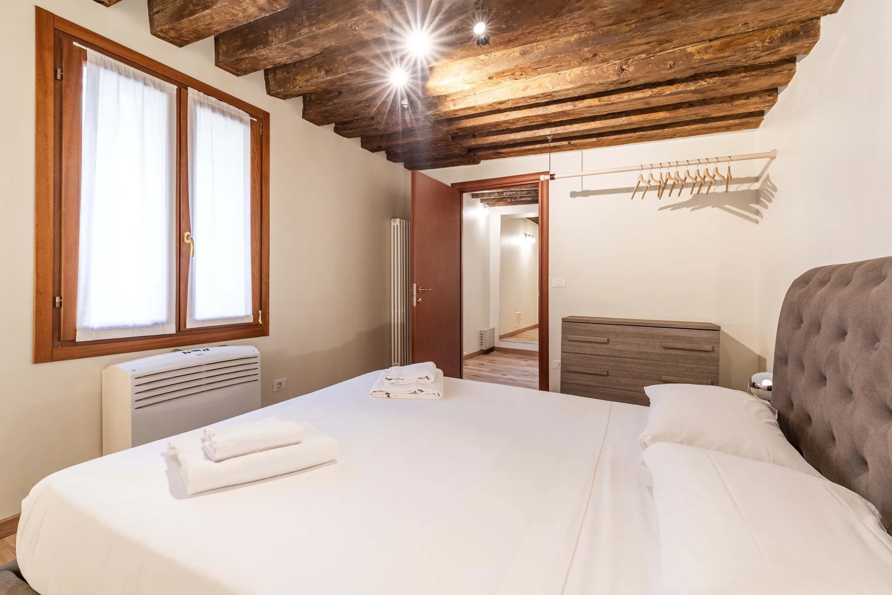 Un dormitorio con una cama grande, una ventana de madera y vigas expuestas en el techo.