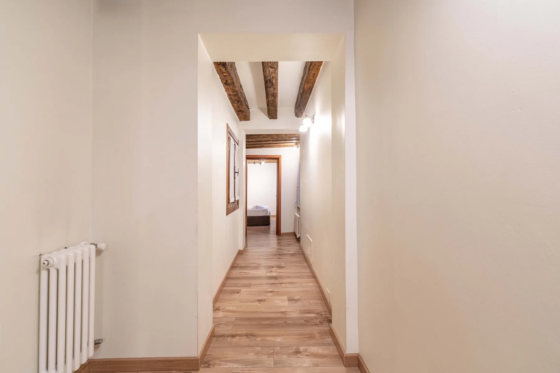 Un pasillo estrecho con suelo de madera y vigas expuestas en el techo.