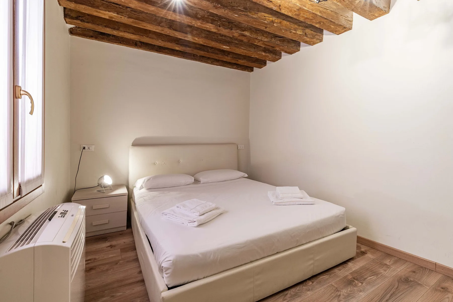 Un dormitorio con una cama bajo vigas de madera expuestas.