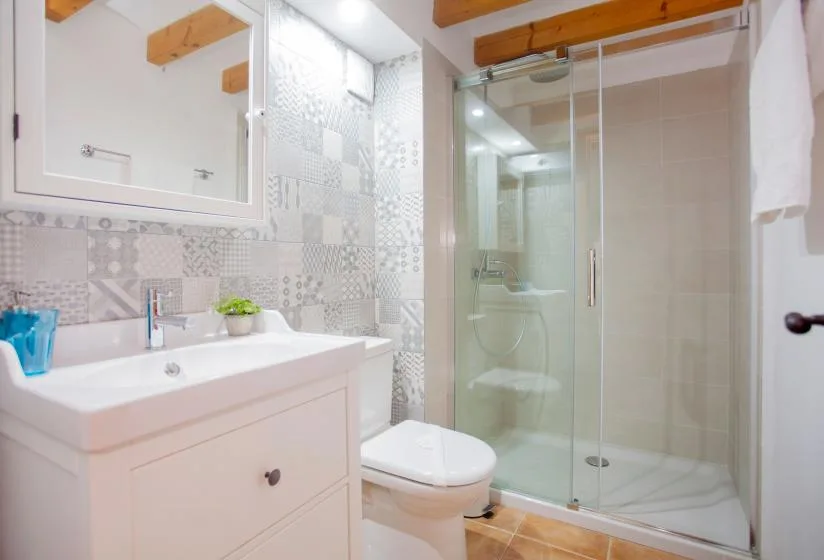 A bright bathroom with a vanity, patterned tile, and glass shower.