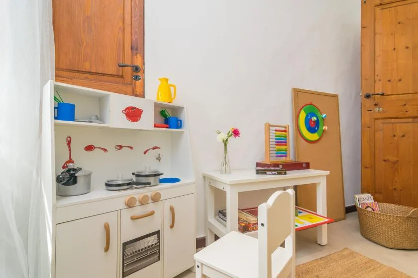 A children’s playroom with a toy kitchen, a small table, and colorful toys.