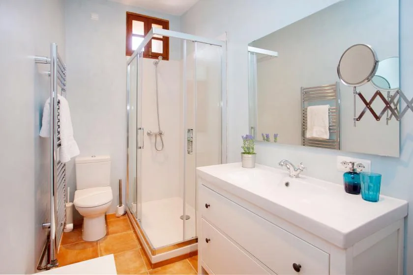A bright bathroom with a glass shower, toilet, and sink vanity.
