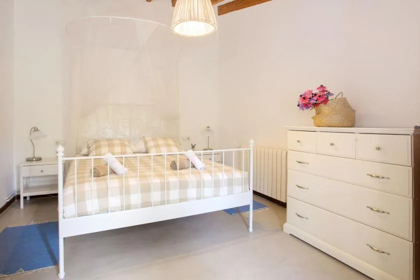 A bedroom with a white bed and a chest of drawers.