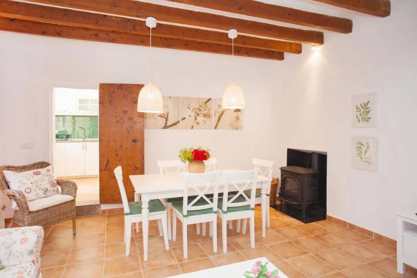 A bright dining area with a white table and chairs beneath exposed wooden ceiling beams.