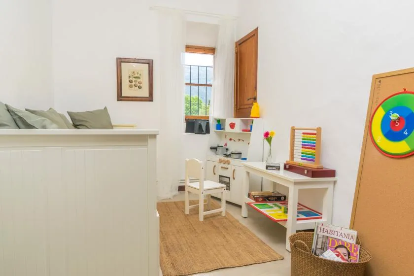 A bright children's playroom with a small table, chairs, and colorful toys.