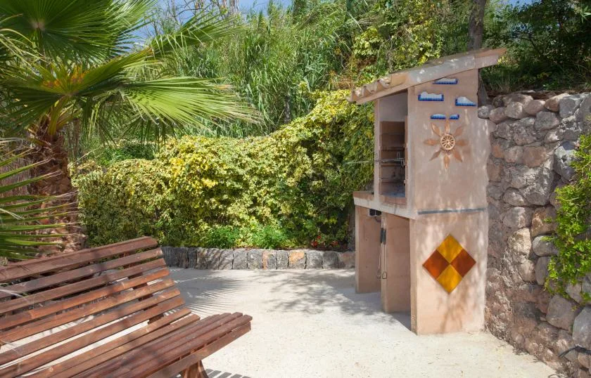 A small outdoor shrine stands beside a stone wall, with a wooden bench nearby.