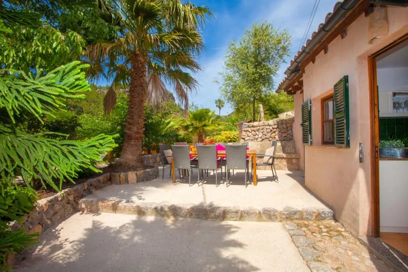 An outdoor patio with a dining table and chairs beside a house.