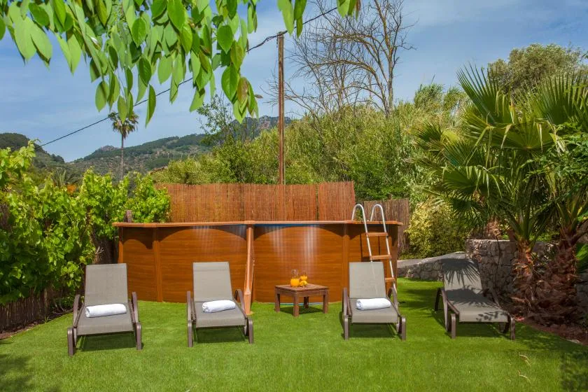 An outdoor pool area with lounge seating and a leafy garden.