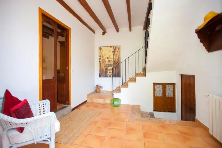 An interior entry hall with terracotta floor tiles and a staircase along the wall.