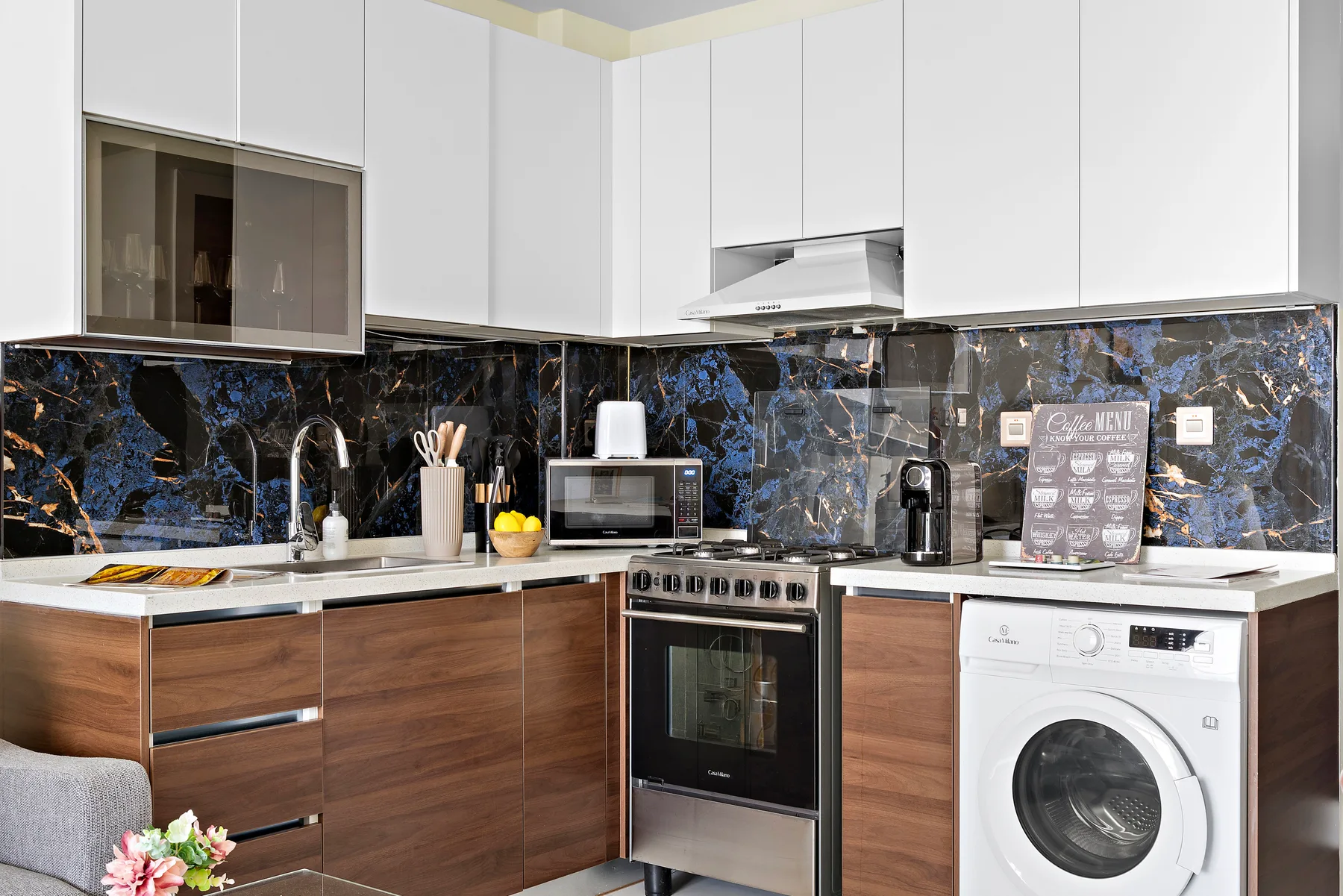 Una cocina moderna con encimeras oscuras, una estufa y una lavadora.