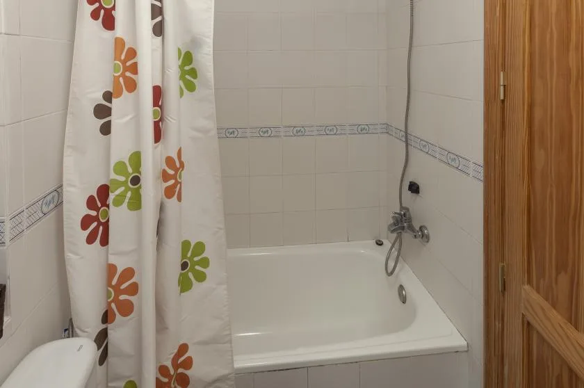 A tiled bathroom with a bathtub and a floral shower curtain.