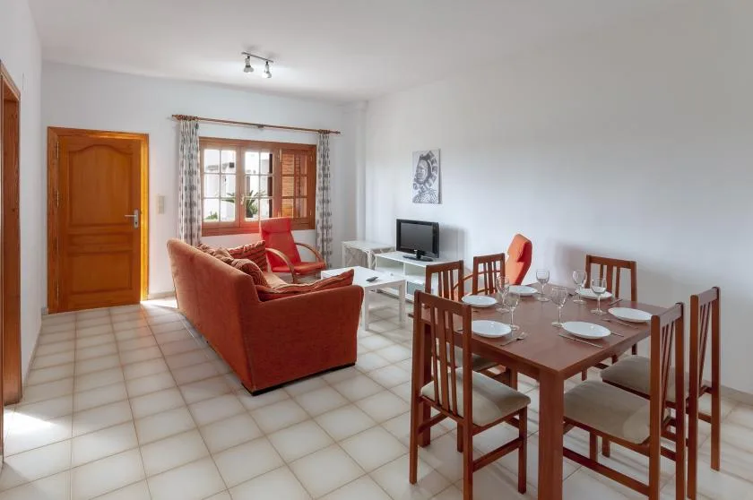 A bright living and dining area with red seating and a wooden dining table.
