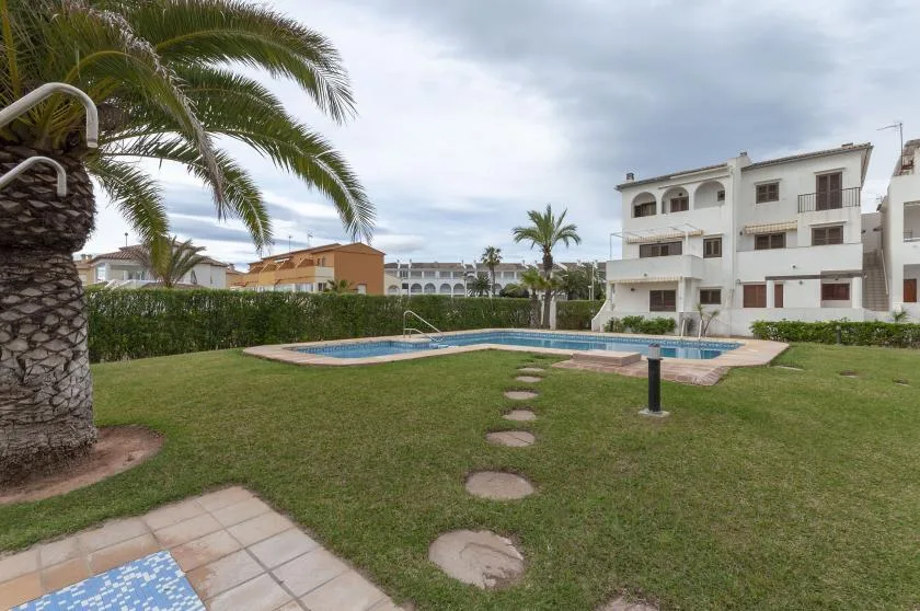 A landscaped outdoor pool area with grass, stepping stones, and surrounding apartment buildings.