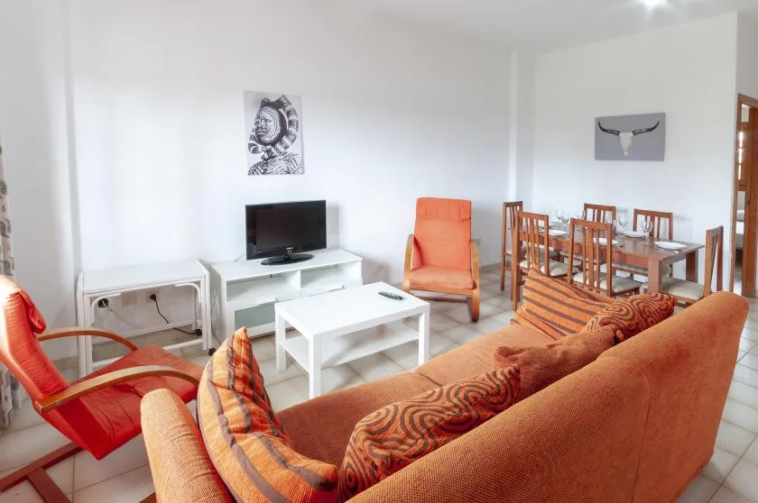 A living room with seating, a television, and a dining table.