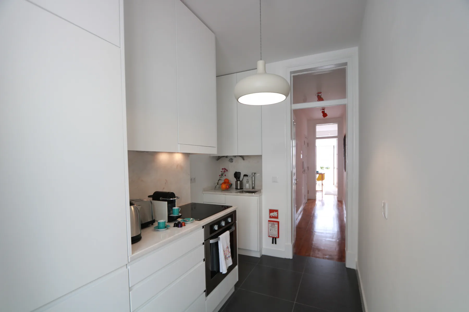 Una cocina compacta con armarios blancos, una encimera y una cocina.