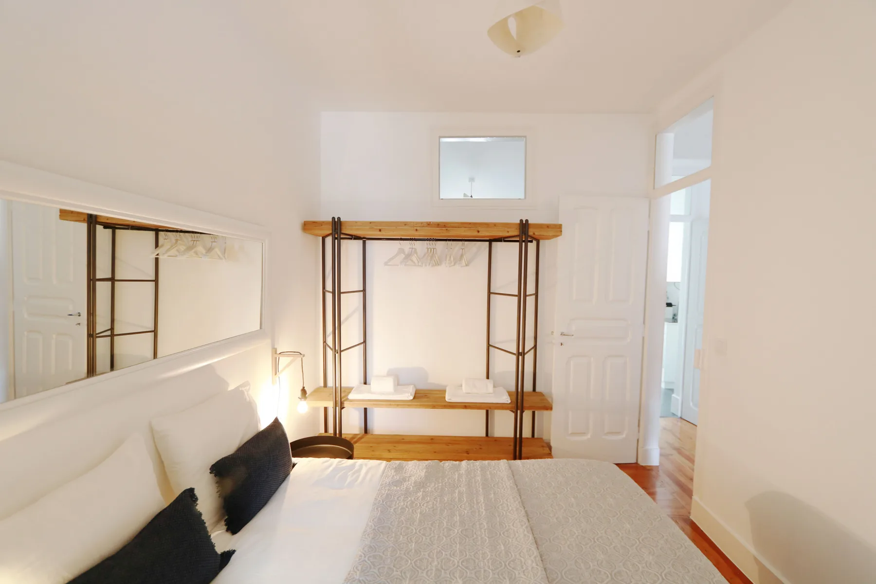 Un dormitorio con una cama y un perchero de madera abierto.