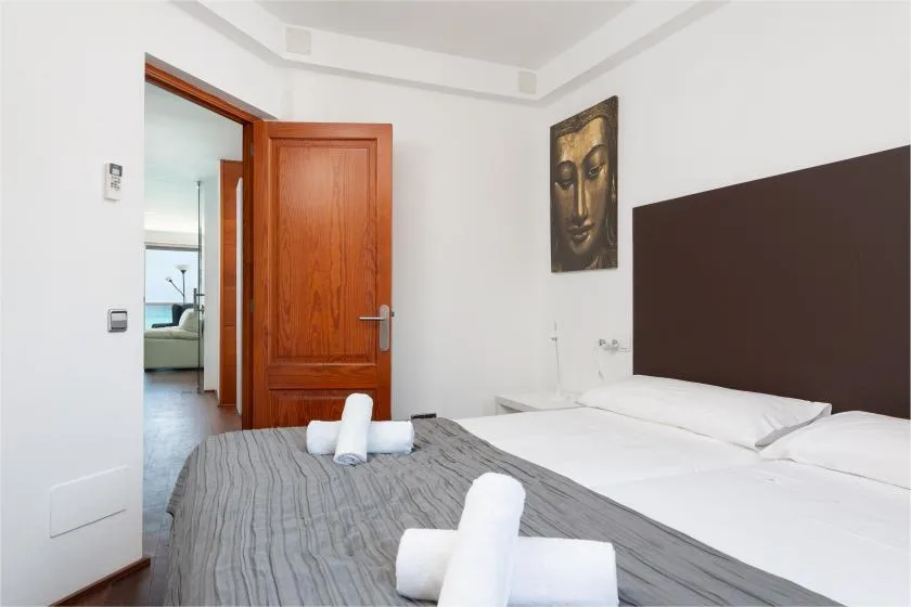 A bedroom with a neatly made bed and an open wooden door.