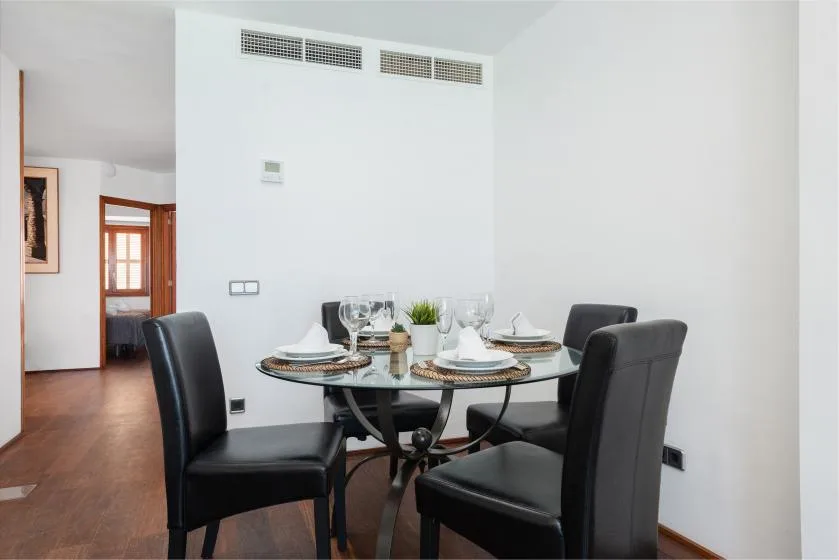 A dining area with a round table set with dishes and chairs.