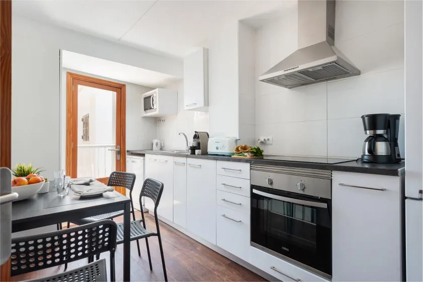 A bright kitchen with white cabinets, a countertop, and a dining table.