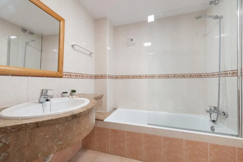 Bathroom with a bathtub and a sink beneath a wall mirror.