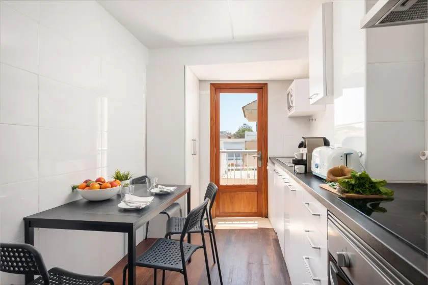 A bright kitchen with a dining table and a glass door opening onto a balcony.