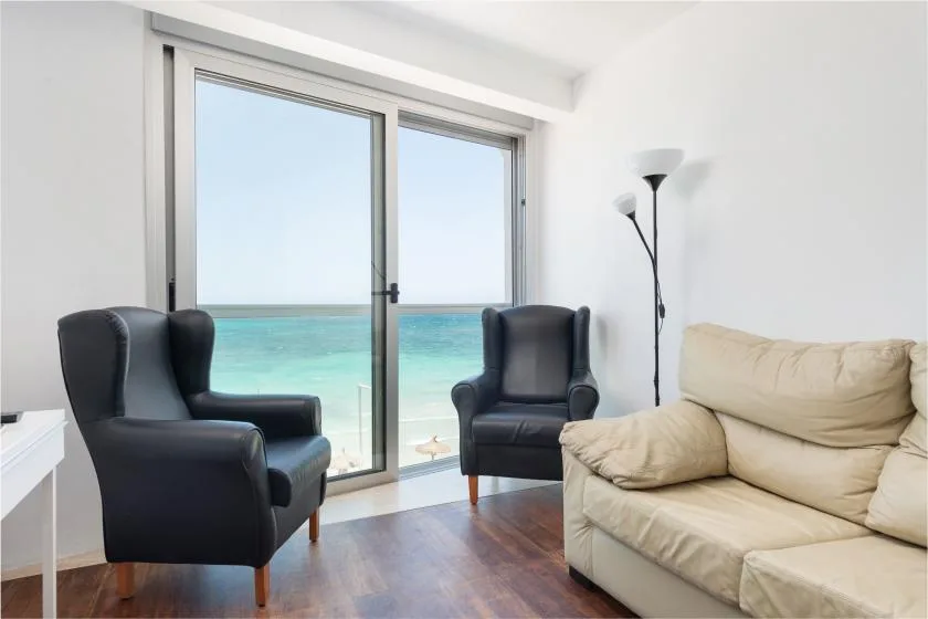 A living room with seating beside glass doors overlooking the ocean.