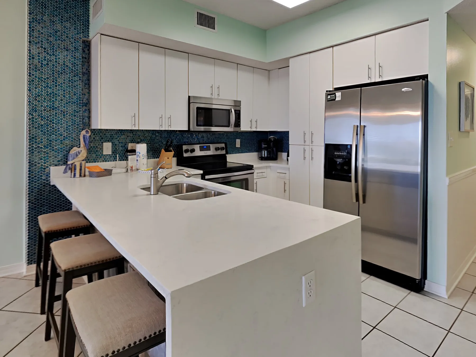 A bright kitchen with white cabinets, a large island, and stainless steel appliances.