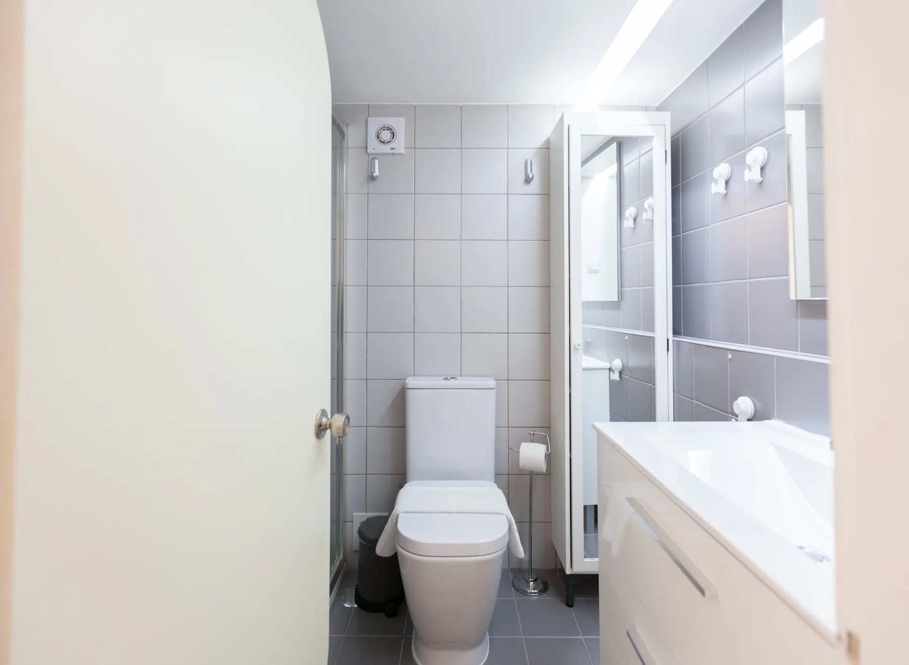 A tiled bathroom with a toilet and a long vanity.