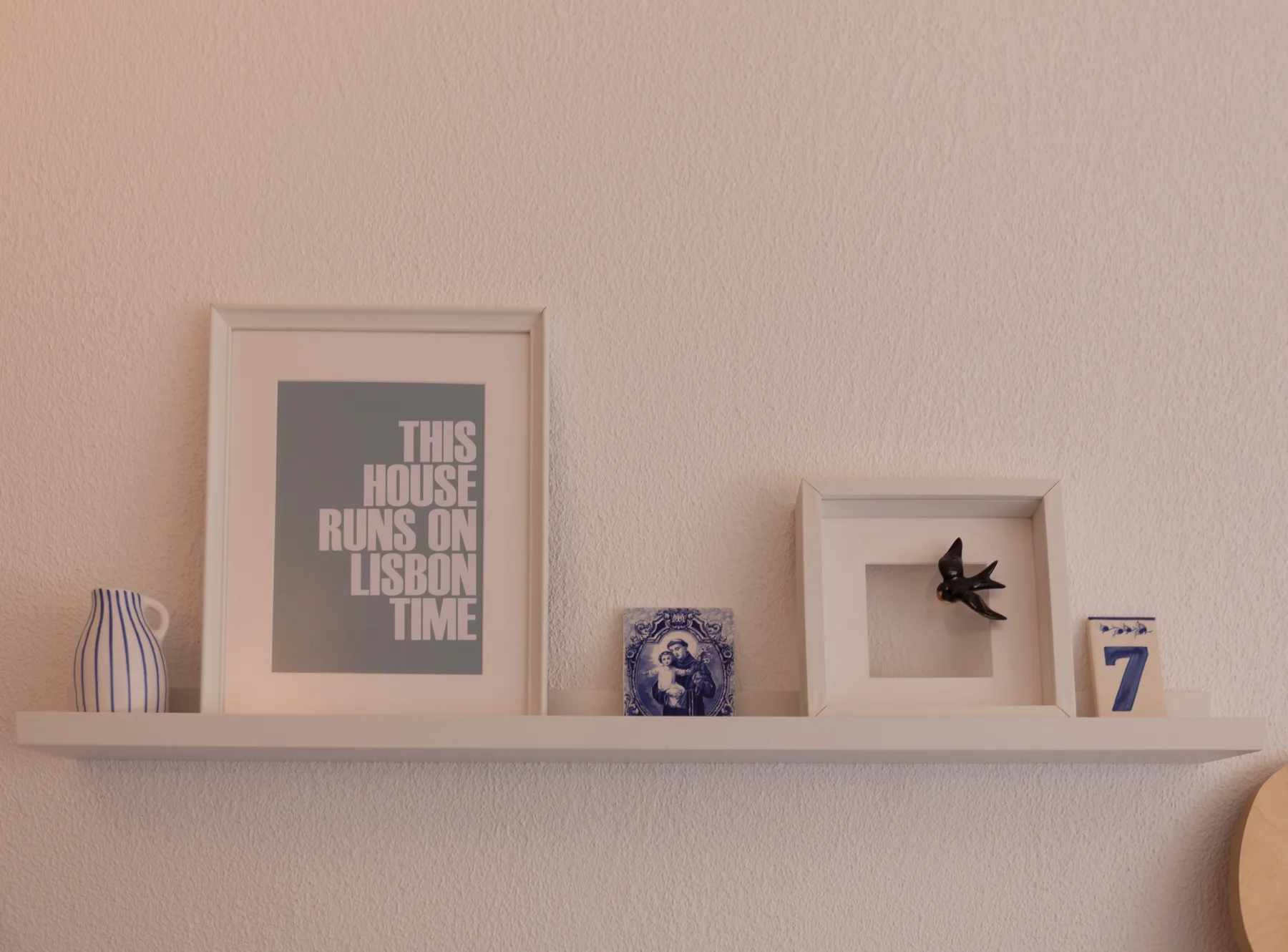 A wall shelf displays framed artwork and small decorative objects.
