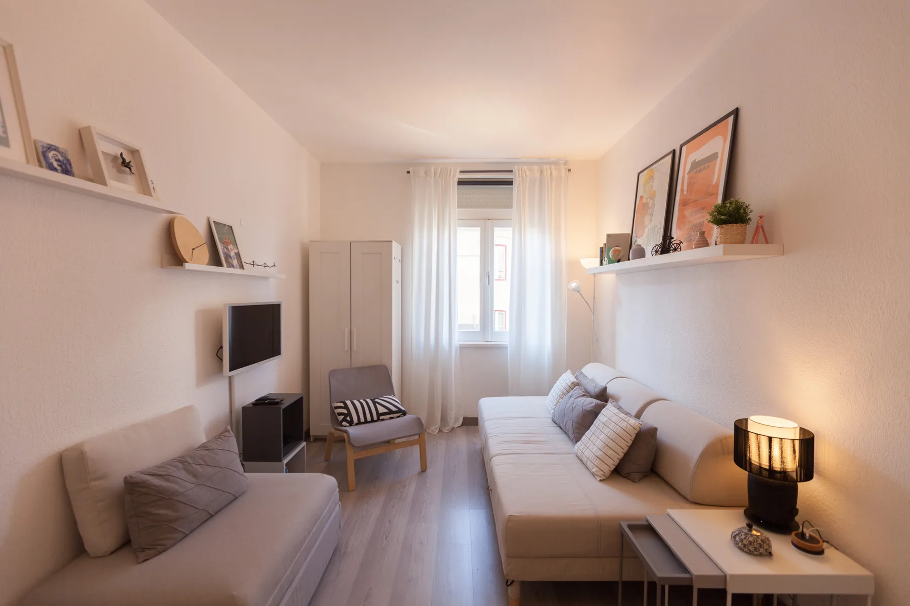 A bright living room with seating, a television, and a window.