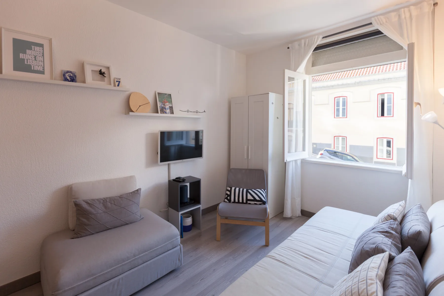 A studio room with seating, a bed, and a large open window.