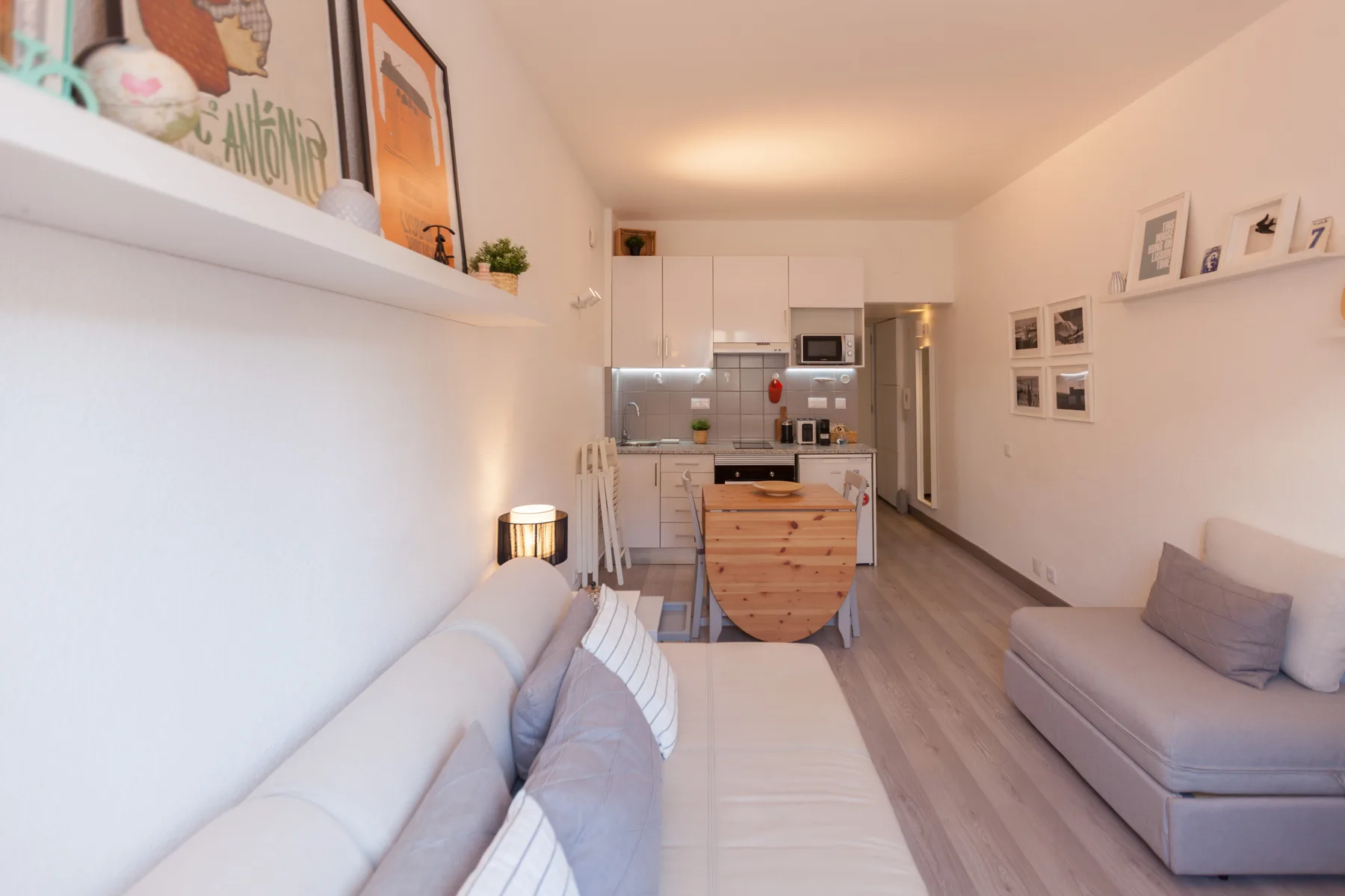 A bright studio interior with seating and a compact kitchen at the far end.