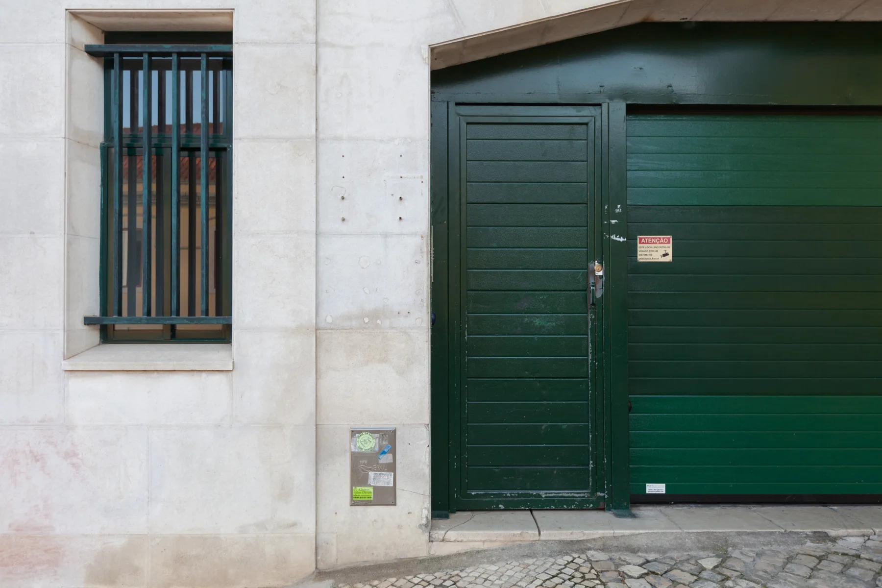 A dark green entrance door and garage door set in a pale stone facade.