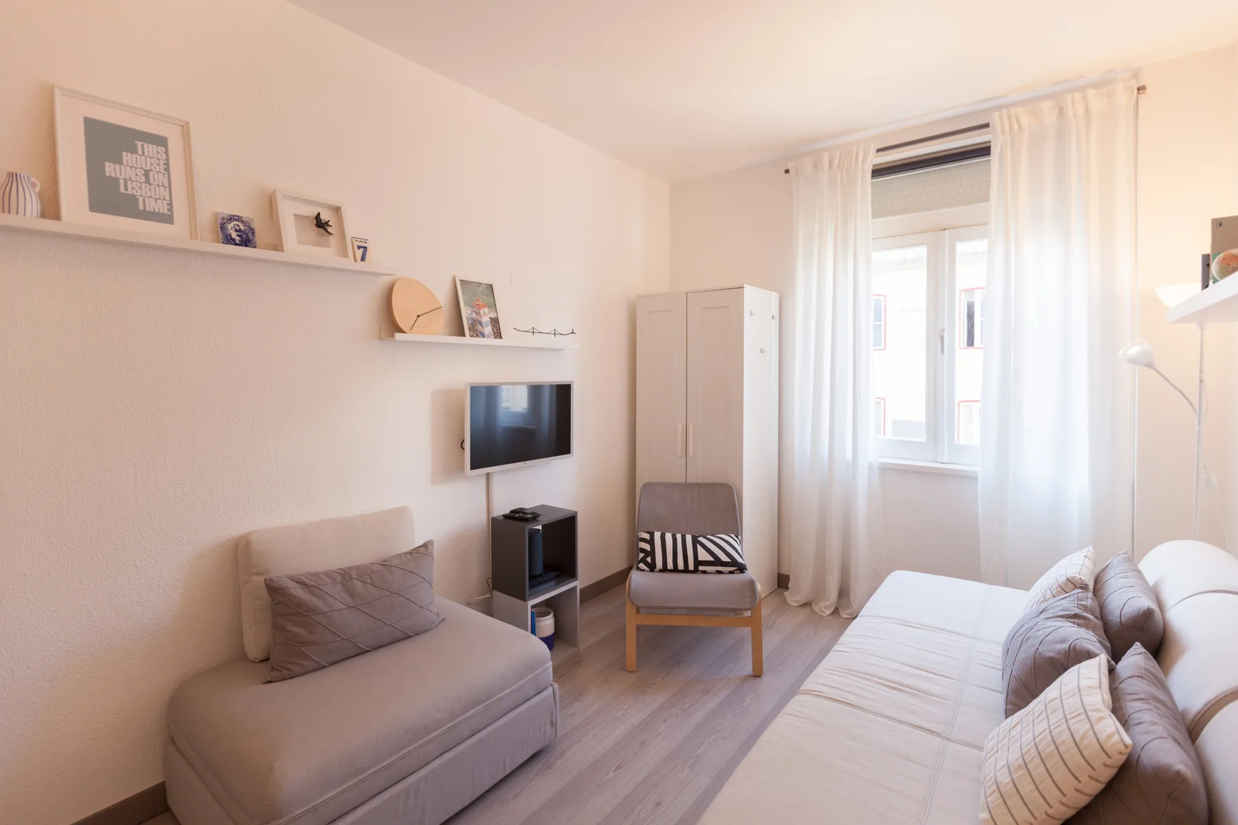 A bright studio living area with seating, a television, and a window.