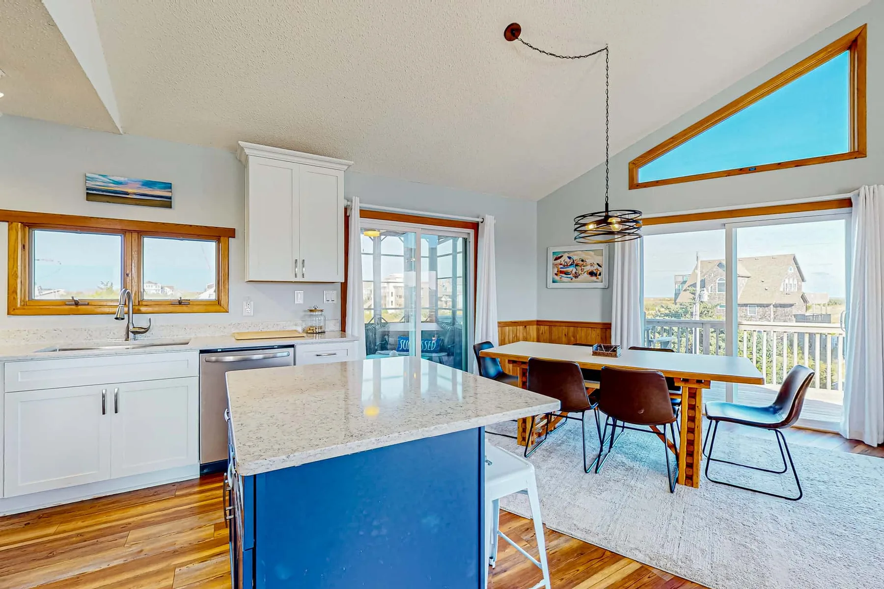 A bright kitchen and dining area with an island and large windows.