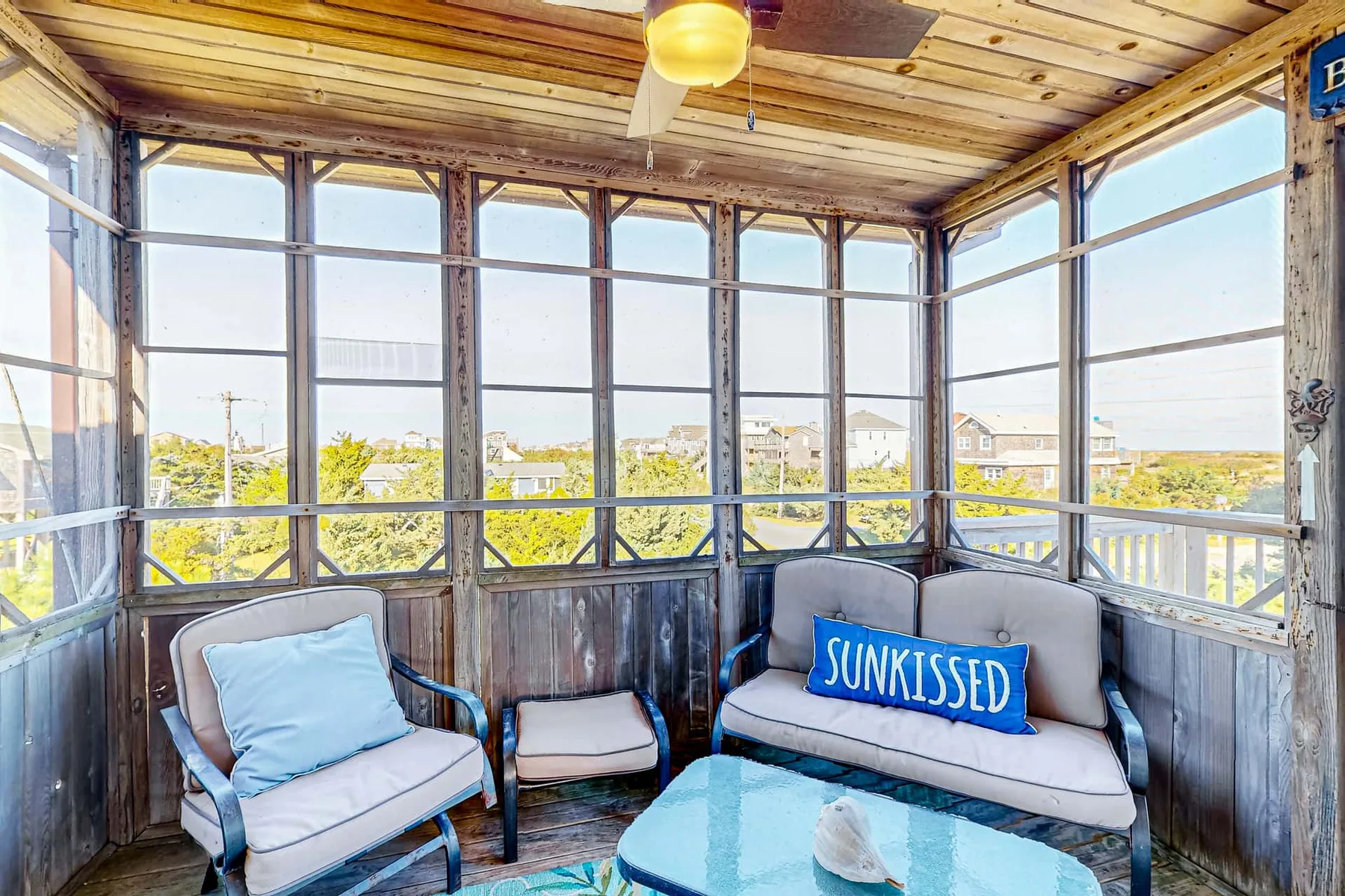 A bright enclosed porch with large windows and seating.