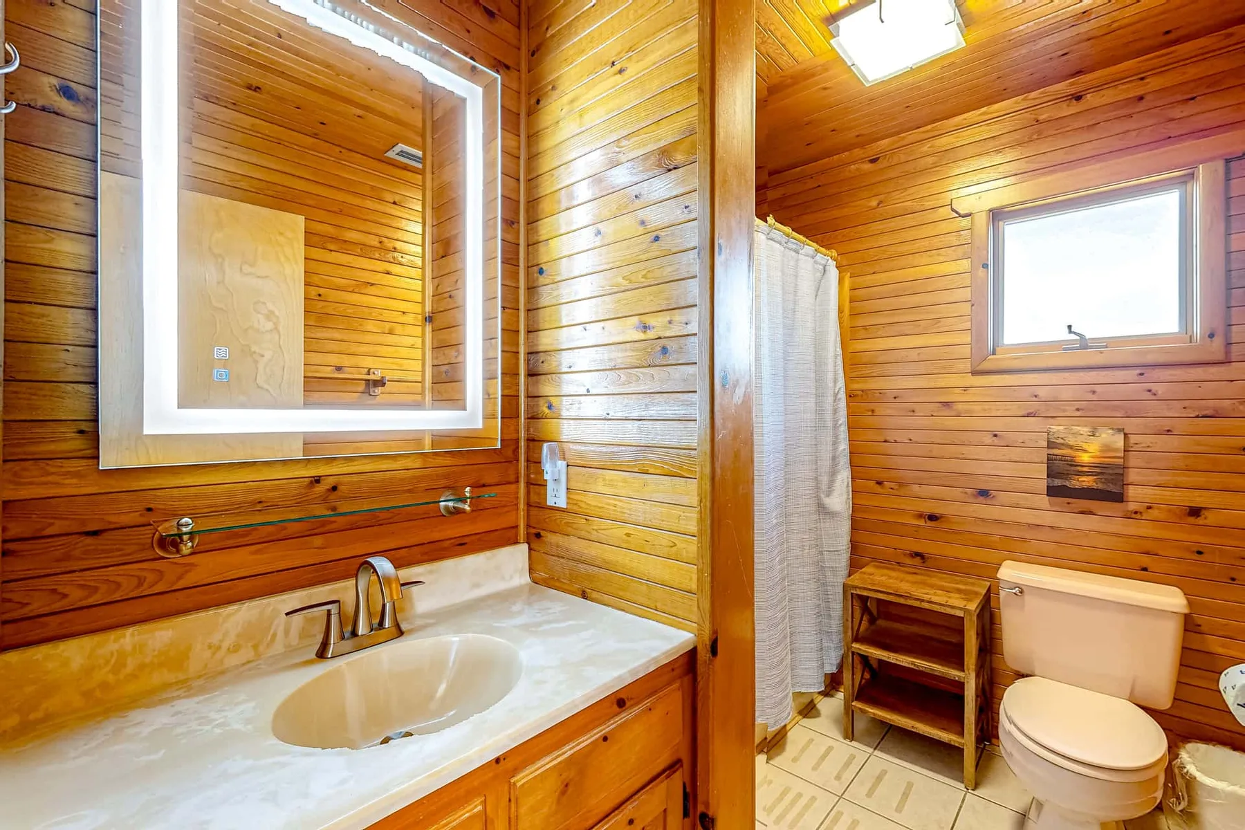 A wood-paneled bathroom with a sink, mirror, shower curtain, and toilet.