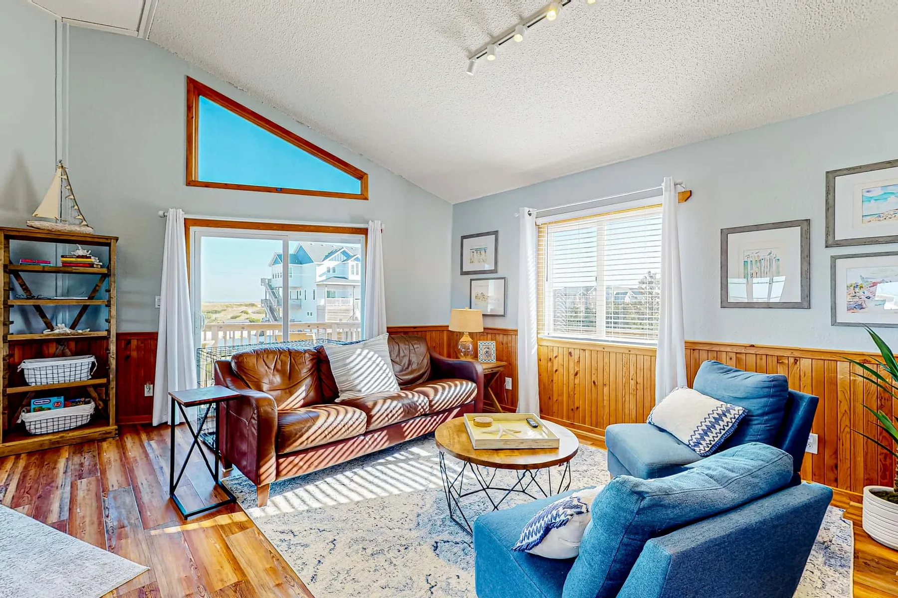 A bright living room with patterned seating and a blue armchair around a coffee table.