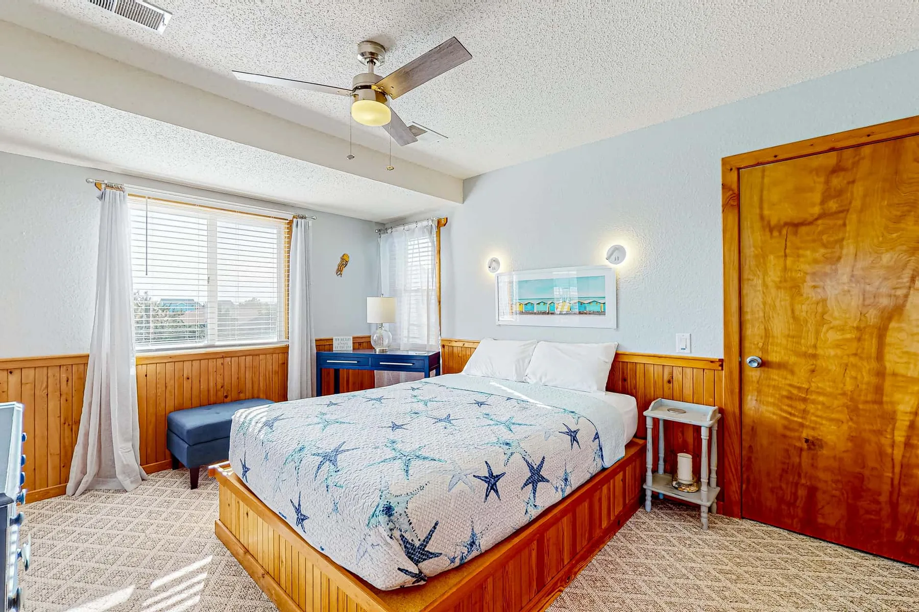 A bedroom with a bed, patterned bedding, and a window with curtains.