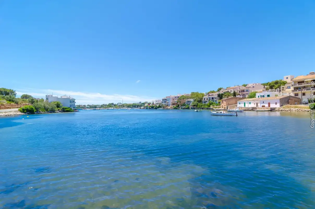 A coastal bay with clear blue water and buildings along the shoreline.