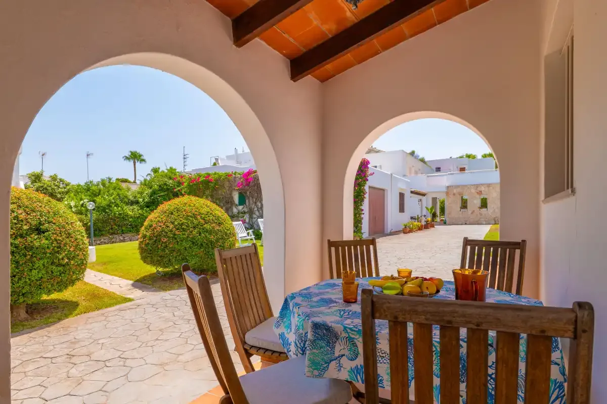 A covered outdoor dining area overlooks a garden and paved courtyard.