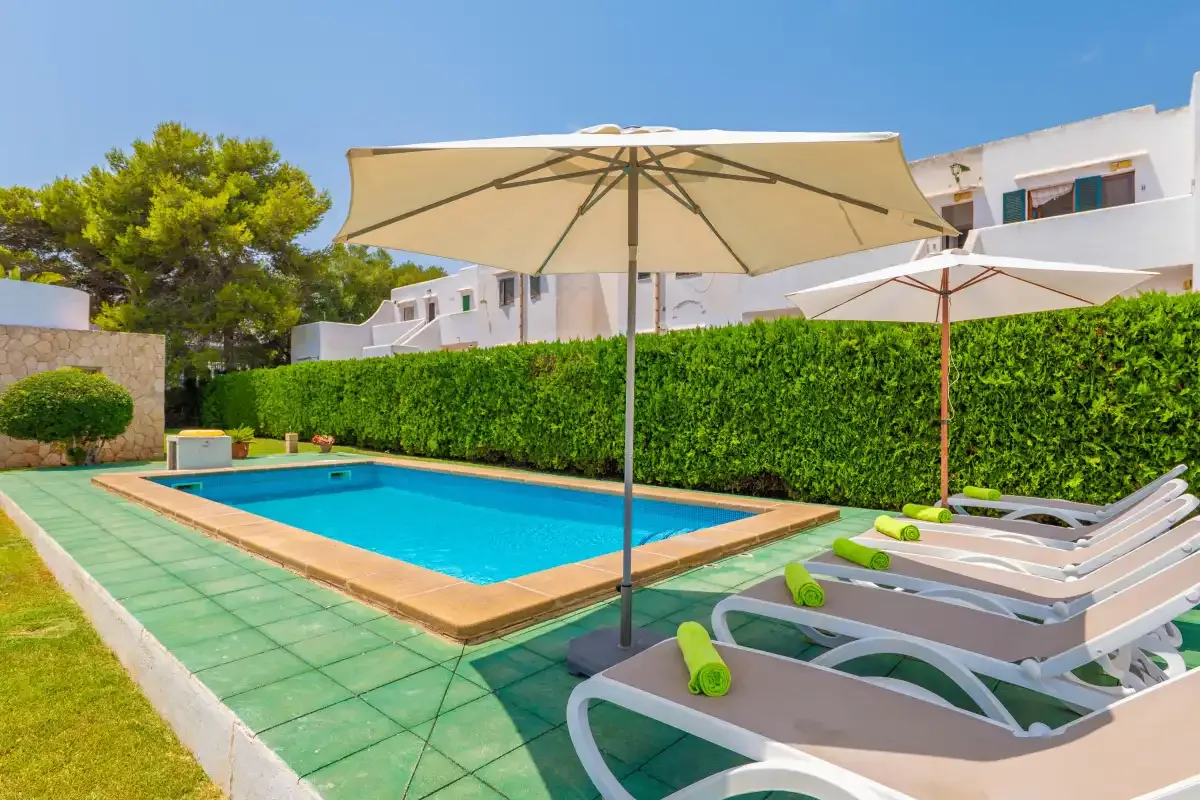 A swimming pool with lounge seating and a large patio umbrella.
