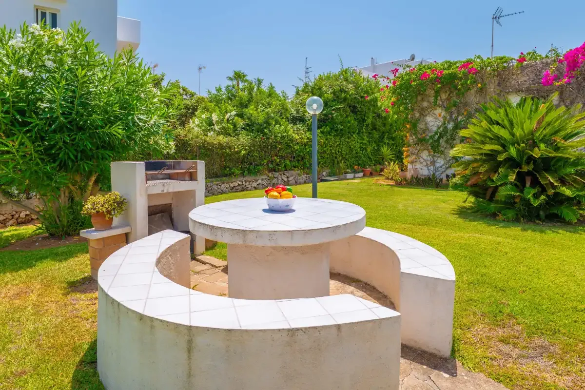 A garden patio with curved built-in seating around a round table and an outdoor fireplace.
