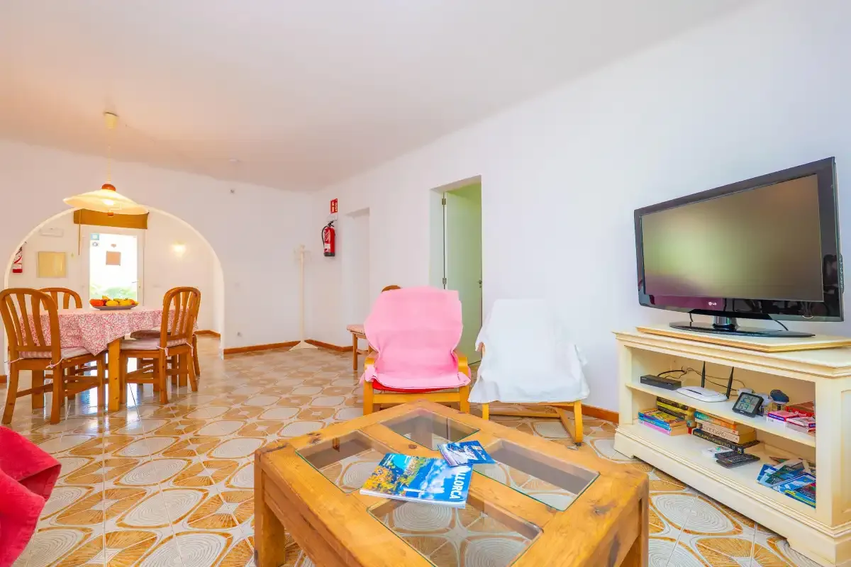 A living room with a television, seating, and a dining area.