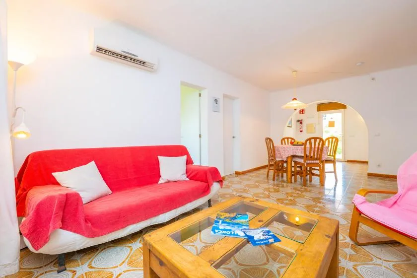 A bright living and dining area with red seating and a wooden coffee table.
